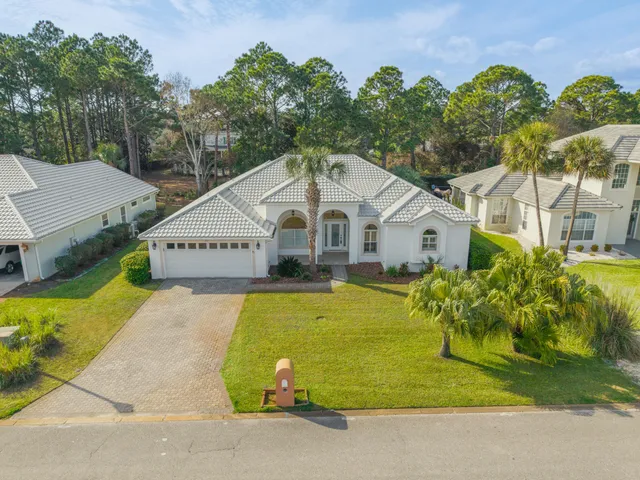a view of a white house with a yard and table and chairs under an umbrella