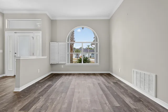 a view of an empty room with wooden floor and a fireplace