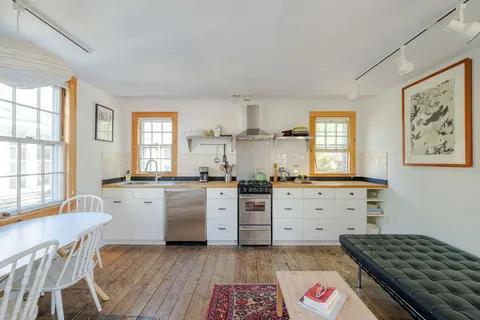 a kitchen with a stove a sink and wooden floor