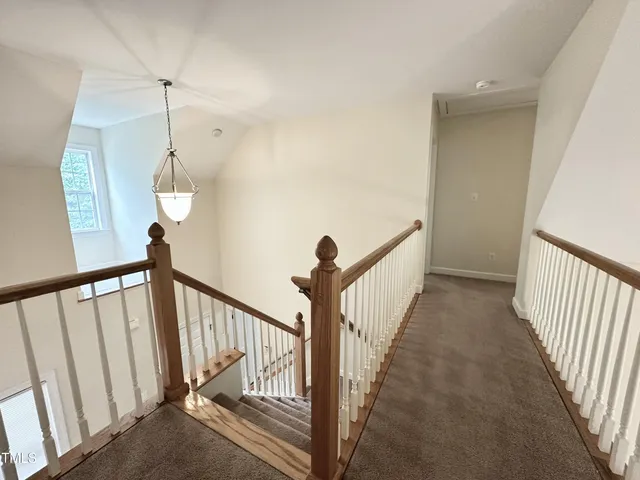 a view of a hallway with wooden floor and stairs