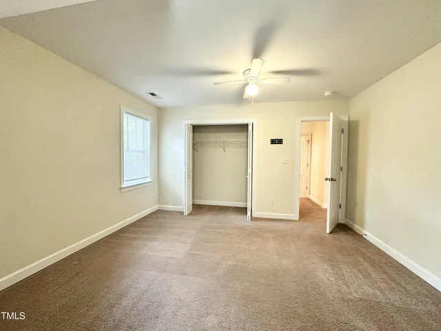 an empty room with windows and fan
