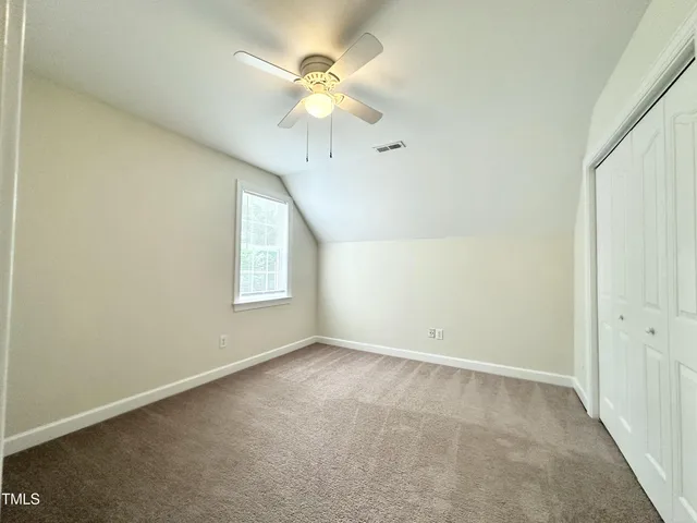 an empty room with a window and a chandelier fan