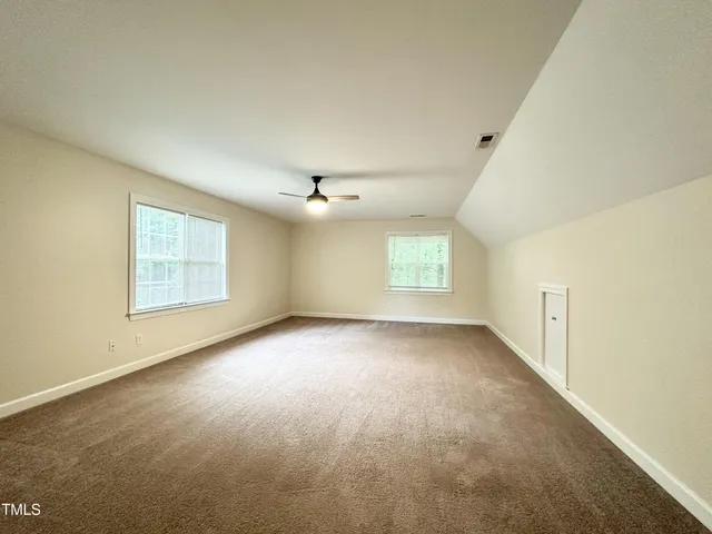 an empty room with windows and ceiling fan