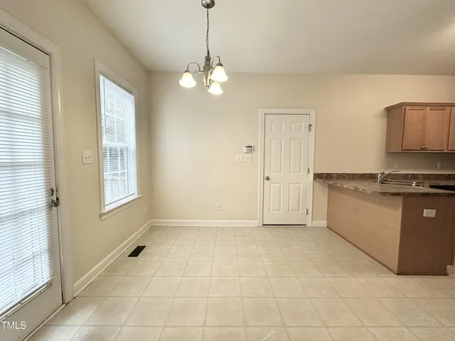 a view of an empty room with window and chandelier