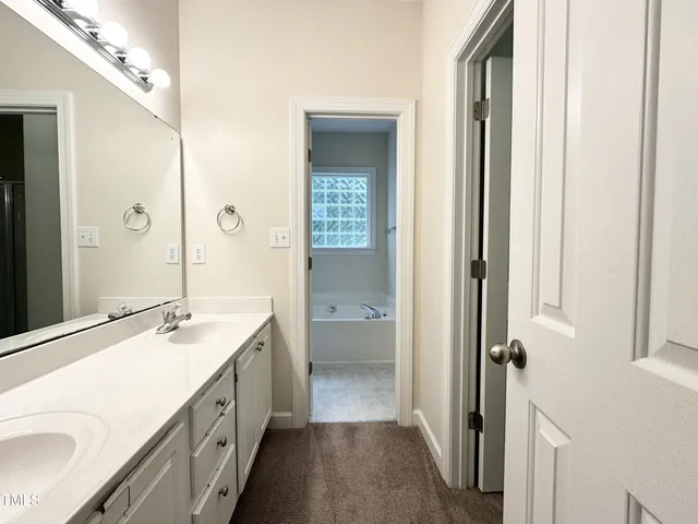 a bathroom with a double vanity sink a mirror and a bathtub
