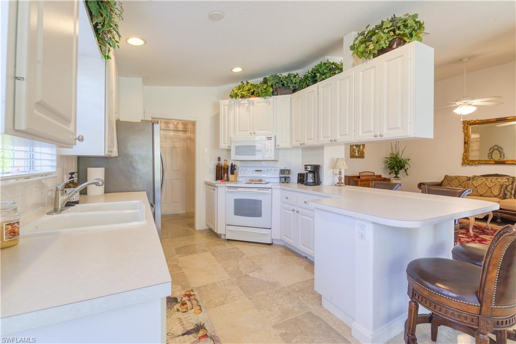 7390 Emilia Lane Naples, FL 34114 - Photo 3 of 25 a kitchen with a refrigerator a sink dishwasher and white cabinets with wooden floor