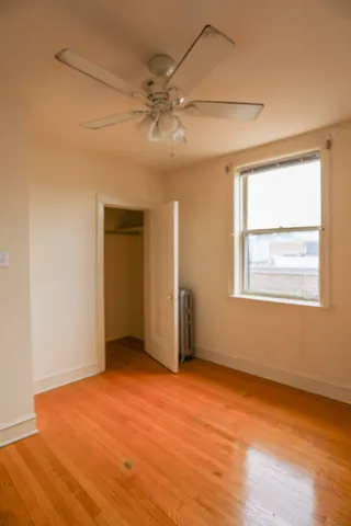 an empty room with wooden floor fan and windows