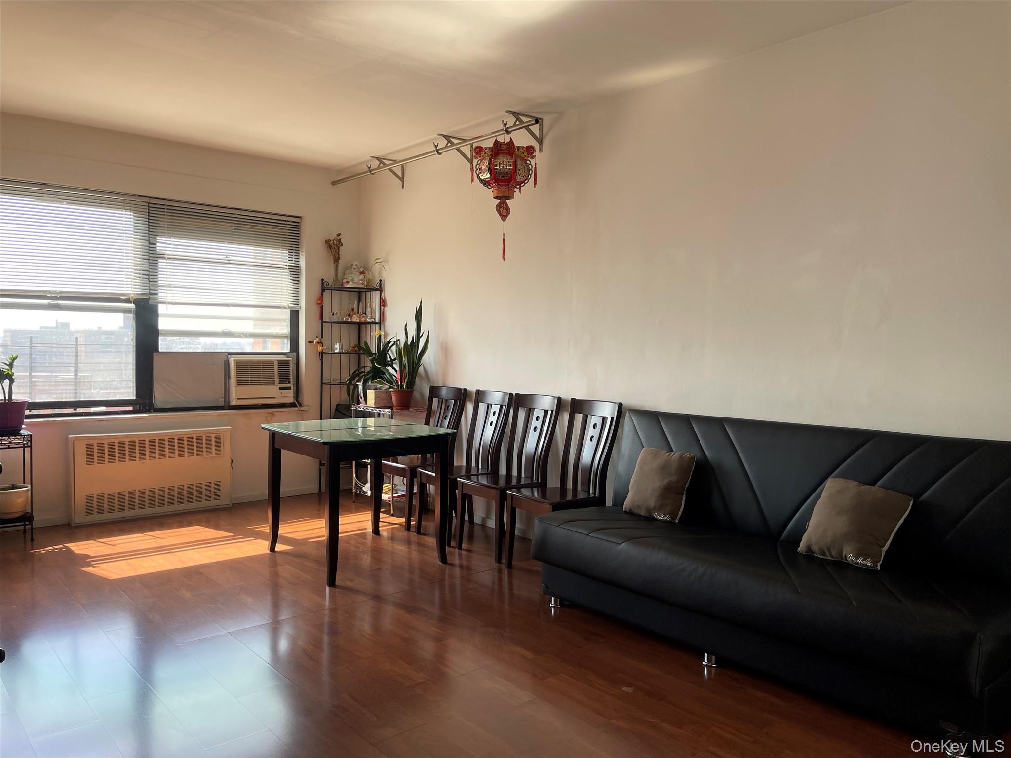 99-72 66th Road, Unit 9S Queens, NY 11374 - Photo 5 of 9 a living room with furniture and a dining table with wooden floor