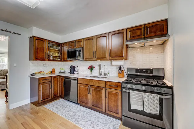 a kitchen with stainless steel appliances granite countertop a stove top oven a sink dishwasher and cabinets with wooden floor