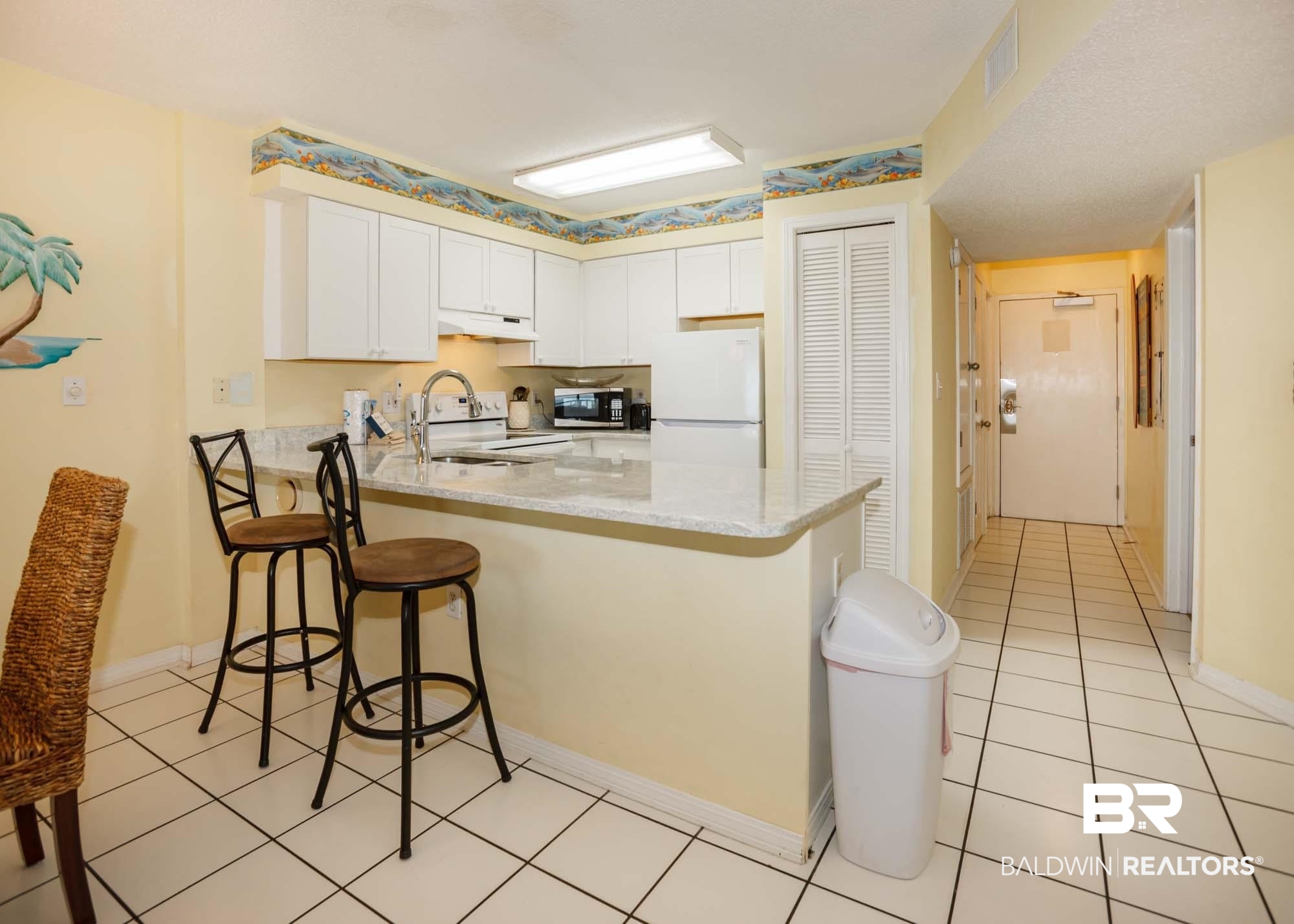 645 Plantation Road, Unit 6311 Gulf Shores, AL 36542 - Photo 38 of 43 Kitchen with white appliances, under cabinet range hood, a peninsula, a breakfast bar area, and white cabinets