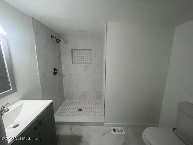 a bathroom with a shower sink vanity and toilet