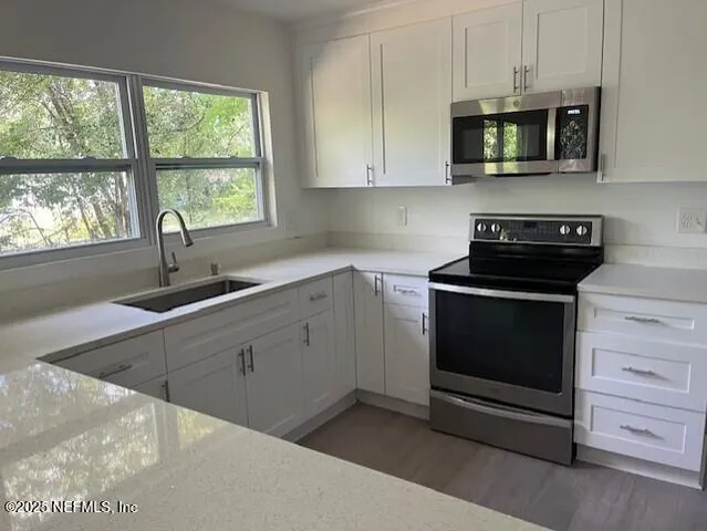a kitchen with stainless steel appliances granite countertop white cabinets a stove a sink and dishwasher next to a window