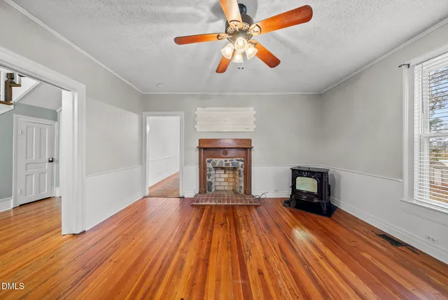 an empty room with wooden floor fireplace and windows