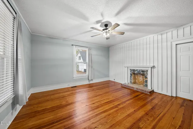 a view of an empty room with window and wooden floor
