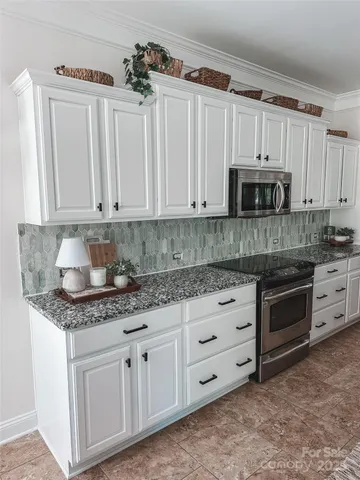 a kitchen with granite countertop white cabinets white stainless steel appliances and a sink