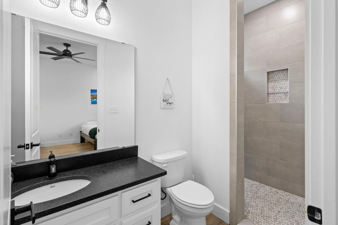 1463 Mountain Valley Road Concan, TX 78838 - Photo 14 of 43 a bathroom with a granite countertop sink toilet a mirror and shower