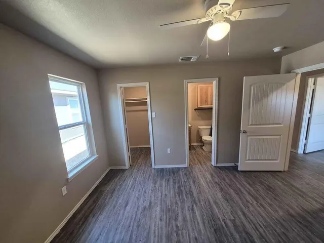 a view of empty room with wooden floor and fan
