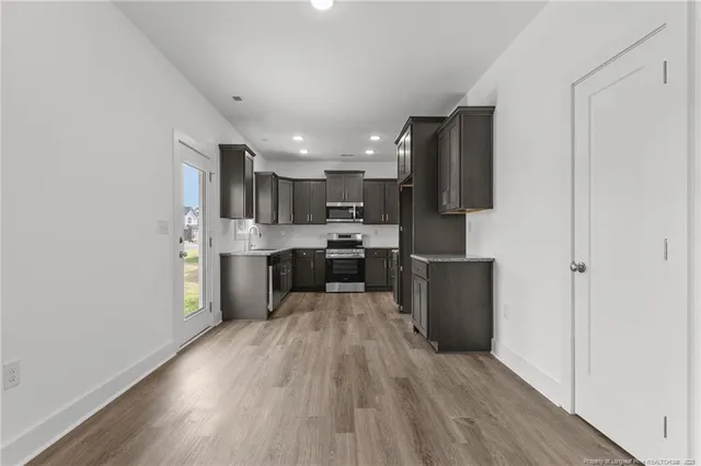 an empty room with wooden floor fireplace and windows