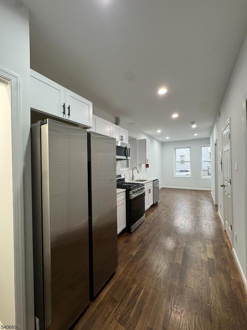 a view of a kitchen with a refrigerator and a stove top oven