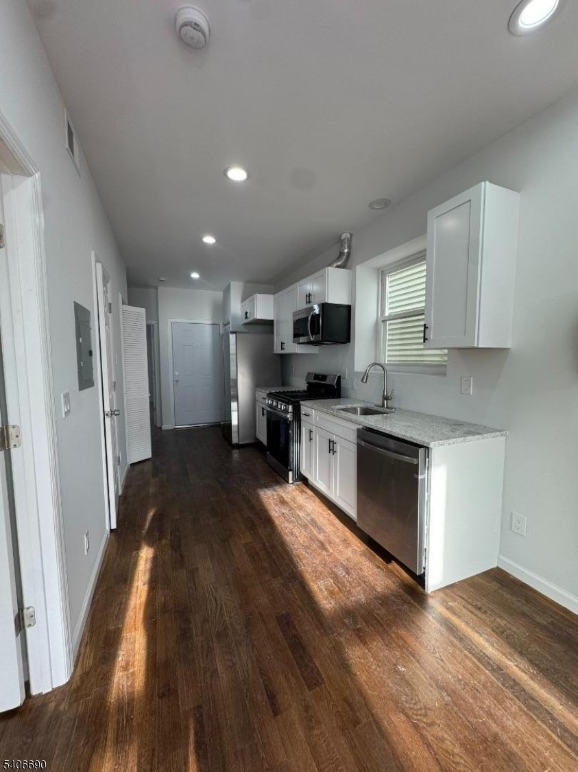 196 Malvern Street, Unit 3 Newark, NJ 07105 - Photo 2 of 16 a large kitchen with cabinets wooden floor and stainless steel appliances