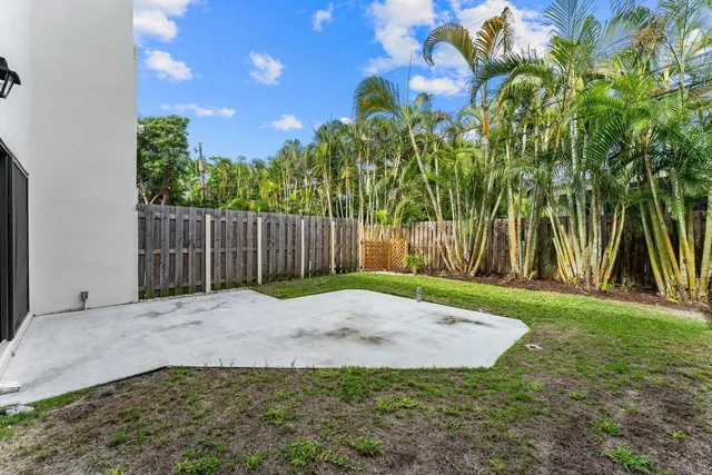 a view of a white house with a small yard and wooden fence
