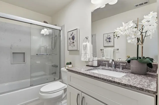 a bathroom with a granite countertop sink a toilet and shower