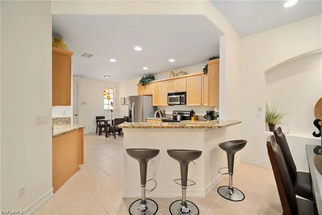 a kitchen with stainless steel appliances kitchen island granite countertop a table and chairs in it
