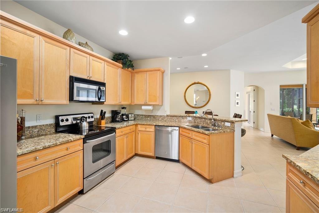 8519 Chase Preserve Drive Naples, FL 34113 - Photo 10 of 29 a kitchen with stainless steel appliances granite countertop a stove top oven a sink dishwasher and cabinets with wooden floor