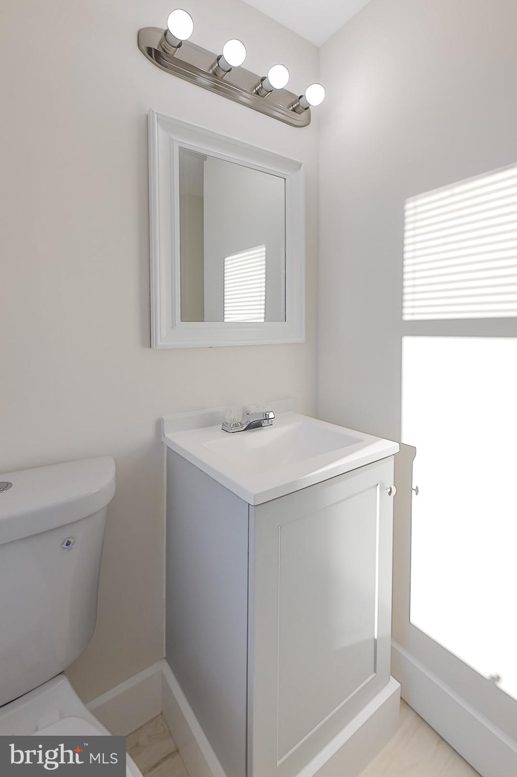 1908 McCulloh Street, Unit 1 Baltimore, MD 21217 - Photo 16 of 24 a bathroom with a sink a toilet a mirror and a window