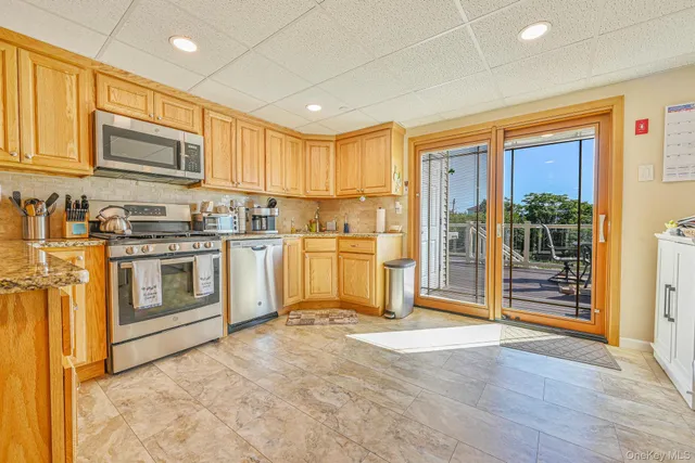 a kitchen with stainless steel appliances granite countertop a stove top oven a sink dishwasher and a refrigerator with wooden floor