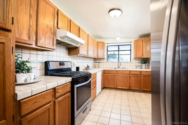 a kitchen with granite countertop a stove top oven cabinets and a refrigerator