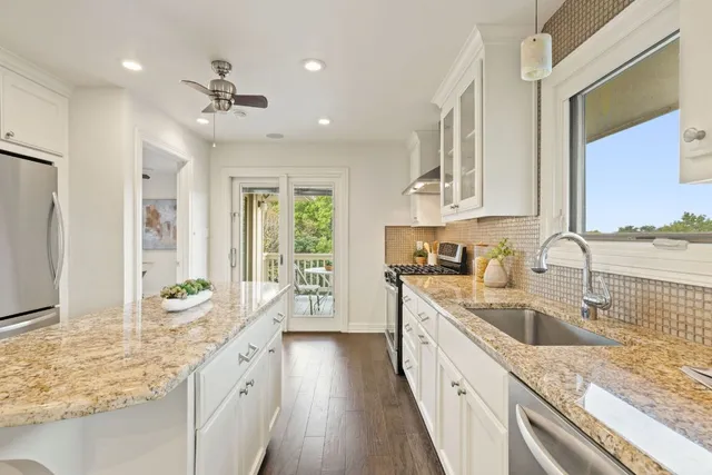 a large kitchen with granite countertop a sink stove and cabinets