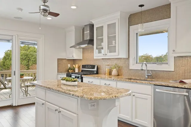 a kitchen with stainless steel appliances granite countertop a sink a stove and cabinets