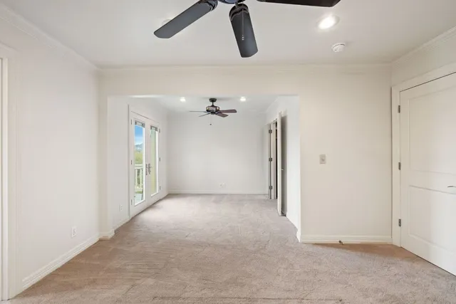an empty room with chandelier fan and windows