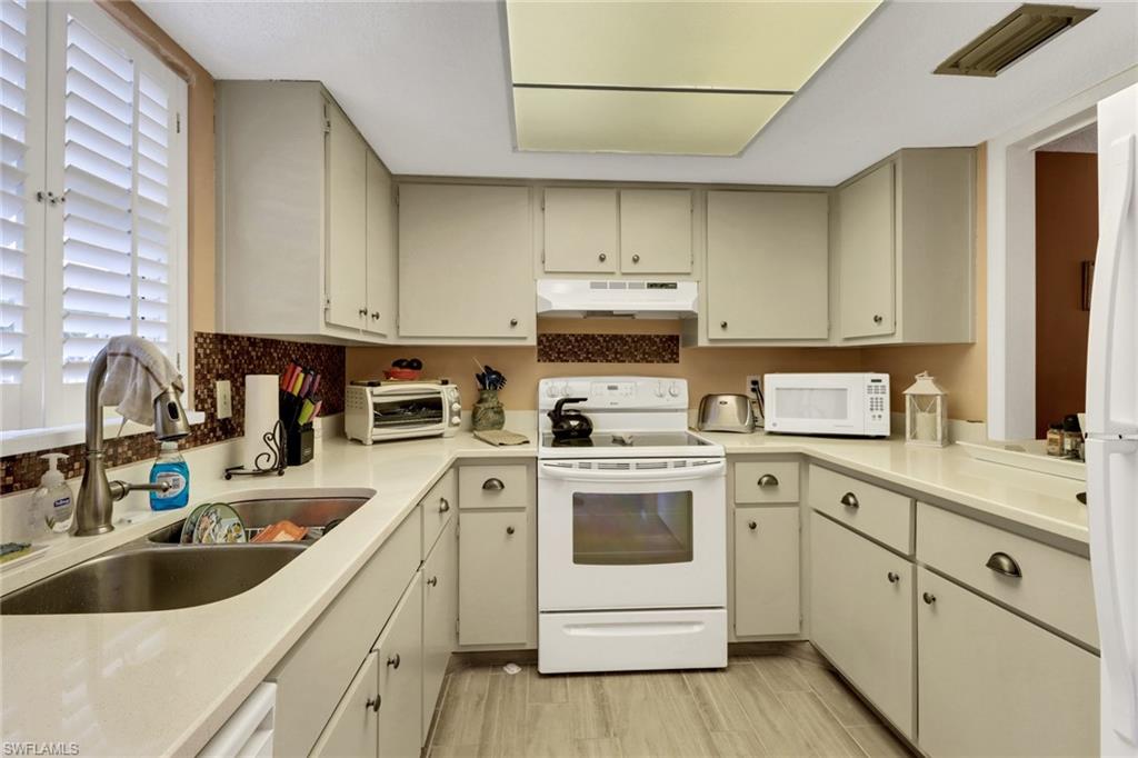 300 Valley Stream Drive, Unit A4 Naples, FL 34113 - Photo 12 of 25 a kitchen with white cabinets sink and white appliances