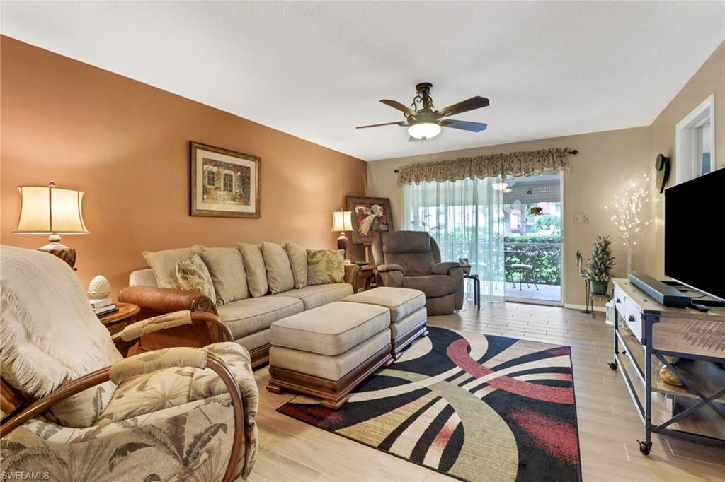 300 Valley Stream Drive, Unit A4 Naples, FL 34113 - Photo 7 of 25 a living room with furniture a flat screen tv and a floor to ceiling window