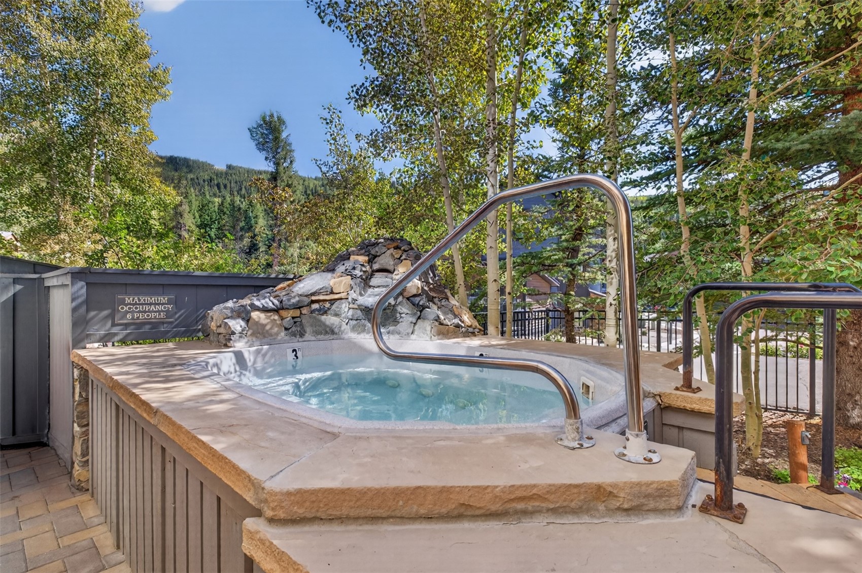 129 River Run Road, Unit 8051 Keystone, CO 80435 - Photo 30 of 50 Outdoor spa with stone surround, integrated rock waterfall feature, and polished metal handrails