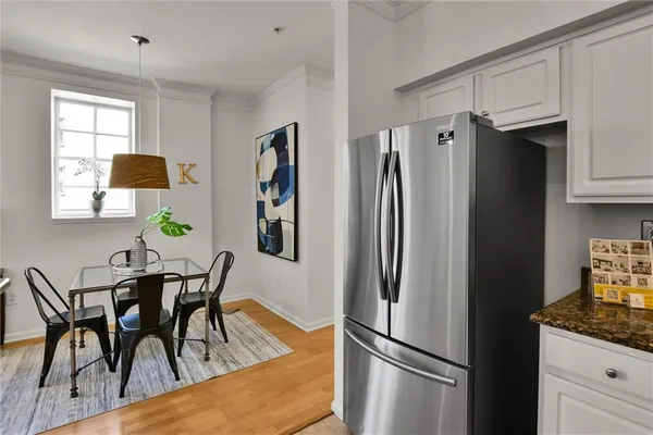 a kitchen with stainless steel appliances granite countertop a refrigerator a stove a dining table and chairs with wooden floor