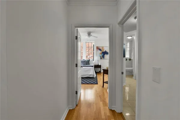 a view of a hallway with wooden floor a livingroom with a white walls