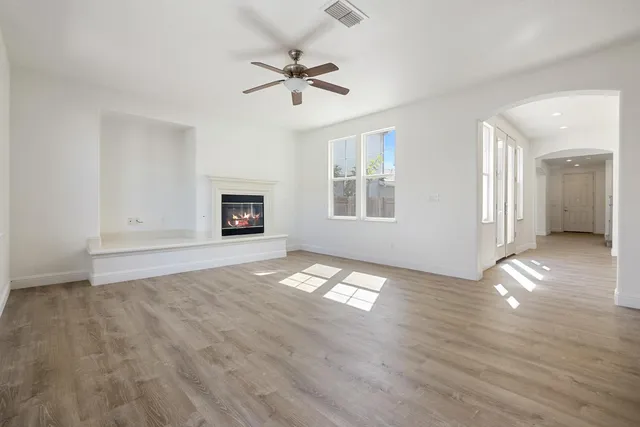 a kitchen with stainless steel appliances granite countertop a refrigerator a sink dishwasher a stove and white cabinets with wooden floor