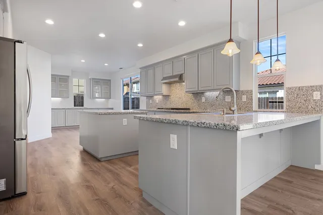 a kitchen with kitchen island a sink stainless steel appliances and wooden floor