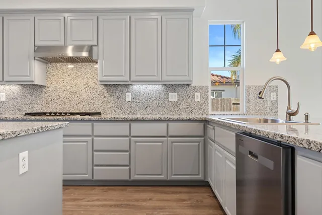 a kitchen with kitchen island granite countertop a sink cabinets and wooden floor