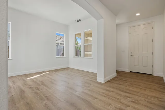 a view of an empty room with window and wooden floor