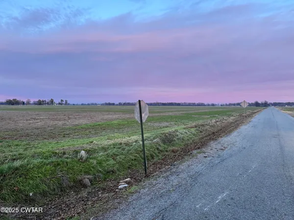 a view of a field with an ocean and a houses