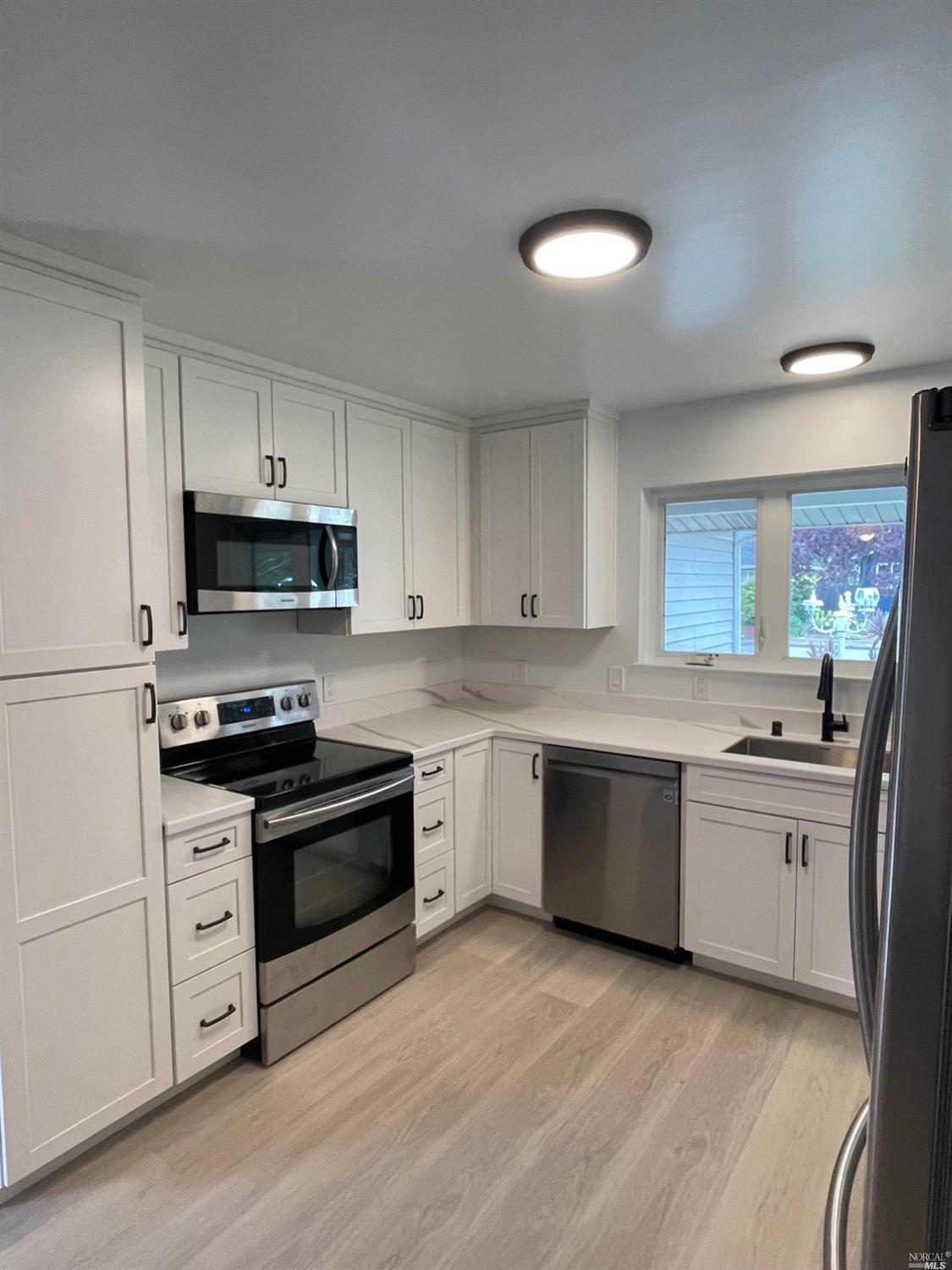 a kitchen with stainless steel appliances granite countertop a stove top oven a sink dishwasher and a refrigerator