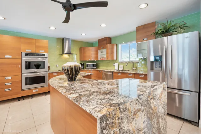 a kitchen with stainless steel appliances granite countertop a refrigerator a stove and a sink