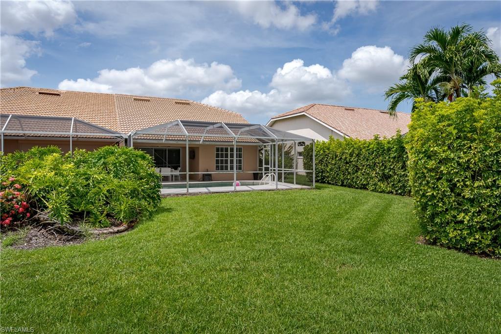 6658 Castlelawn Place, Unit 9 Naples, FL 34113 - Photo 30 of 38 Expansive backyard with manicured lawn and mature privacy hedges