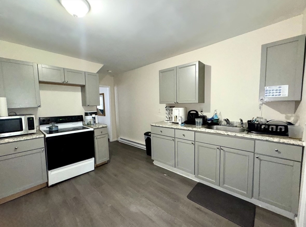 50-52 John Street Pittsfield, MA 01201 - Photo 3 of 24 a large kitchen with stainless steel appliances kitchen island granite countertop a stove a sink and a microwave
