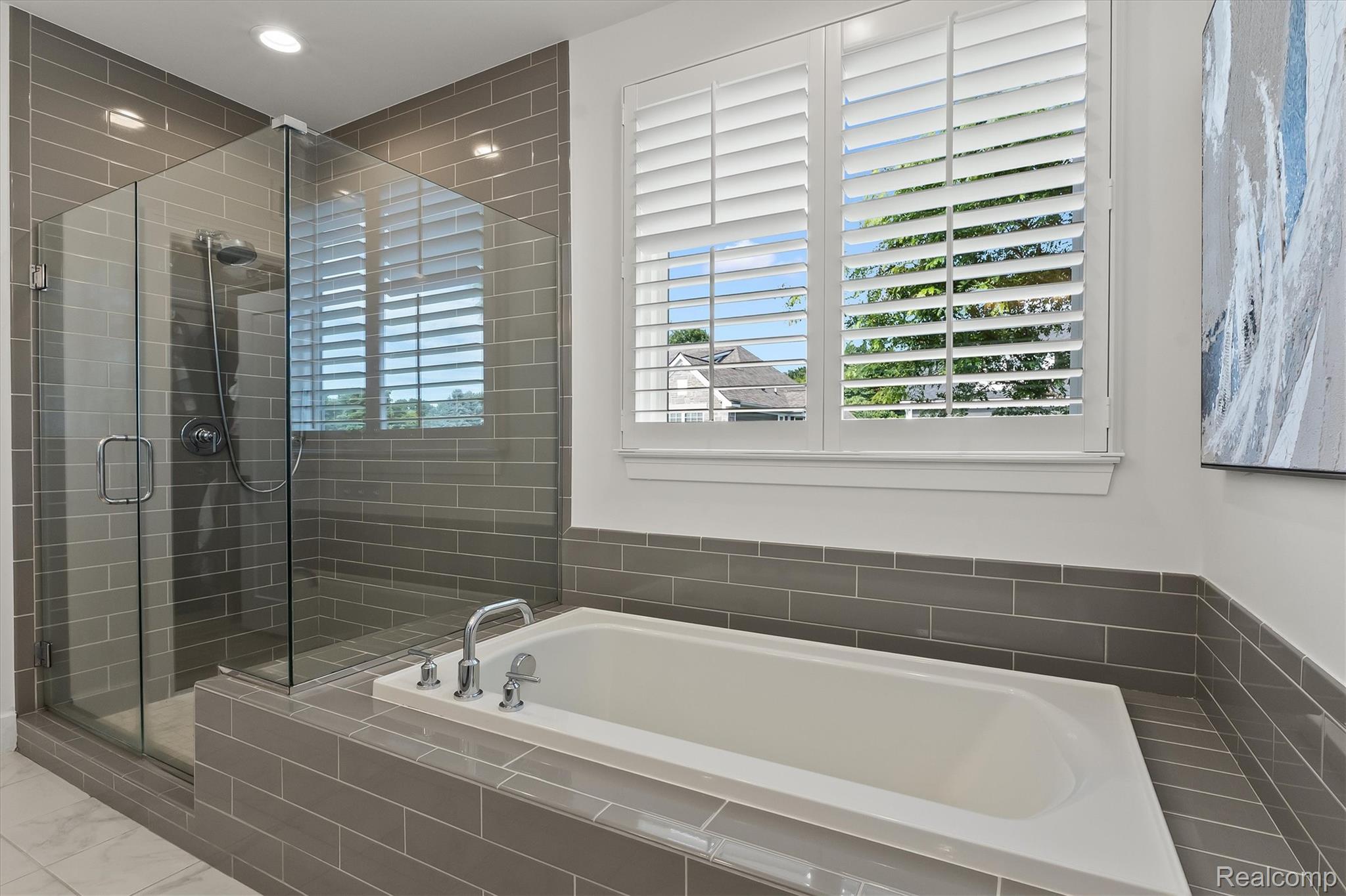 2554 Middleton Street Rochester, MI 48309 - Photo 28 of 38 Soaking tub with chrome fixtures, surrounded by gray subway tile, glass-enclosed shower, and plantation shutters