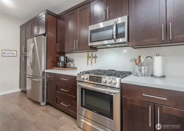 a kitchen with stainless steel appliances granite countertop a stove microwave refrigerator and cabinets